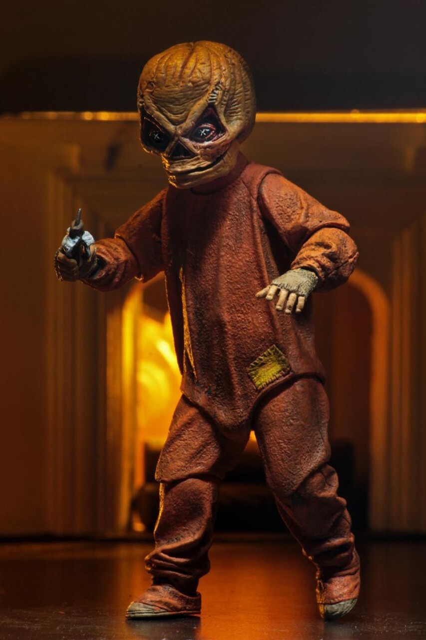 This is a Trick R Treat Sam NECA 7" ultimate action figure and he has a mask with triangle eyes, an orange suit, gloves and he is holding a candy bar knife.