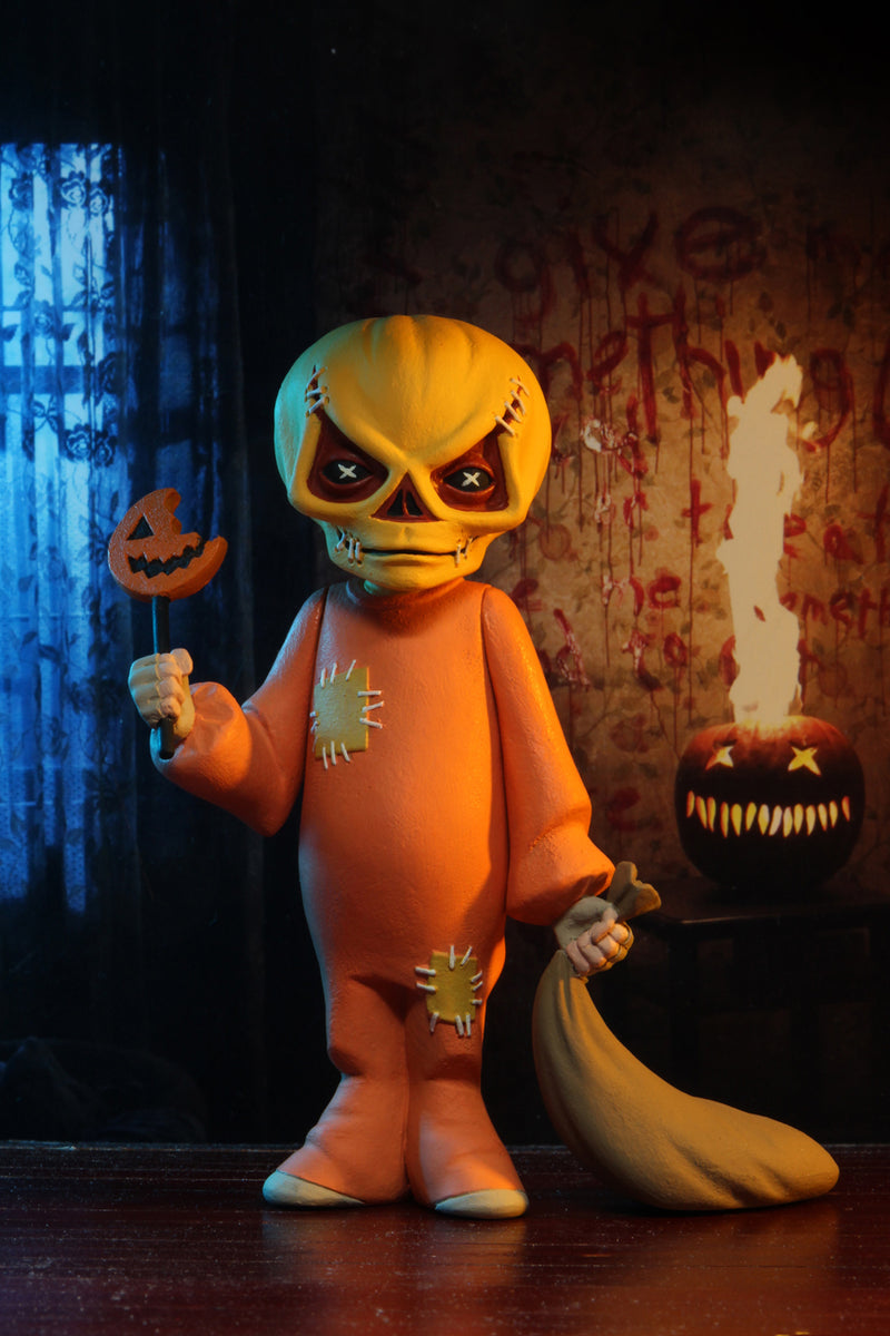 This is the Toony Terrors NECA action figure series 4 Sam from Trick 'R Treat and he has an orange suit, pumpkin head with triangle eyes and a bitten lollipop with a pumpkin with fire behind him.
