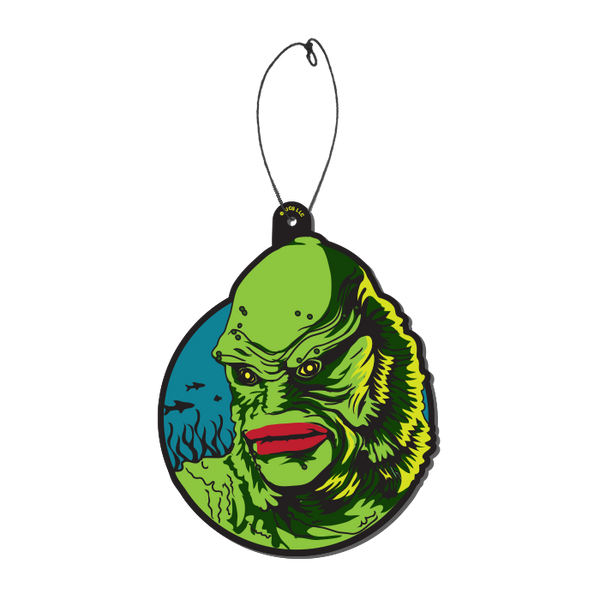 This is a Universal Monsters Creature From the Black Lagoon air freshener by Trick Or Treat and he has green skin and gills and scales with red lips and is in front of a blue circle and fish, with a plastic hanger.