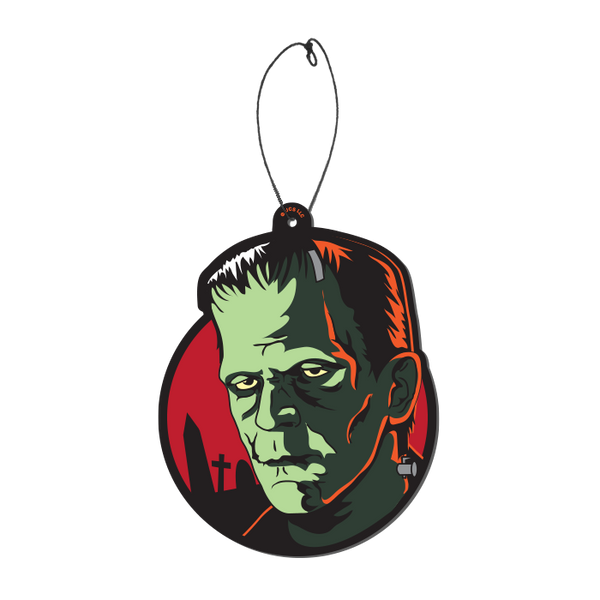 This is a Universal Monsters Frankenstein air freshener by Trick Or Treat and he has green skin, black hair and is in front of a red circle with headstones, with a plastic hanger.