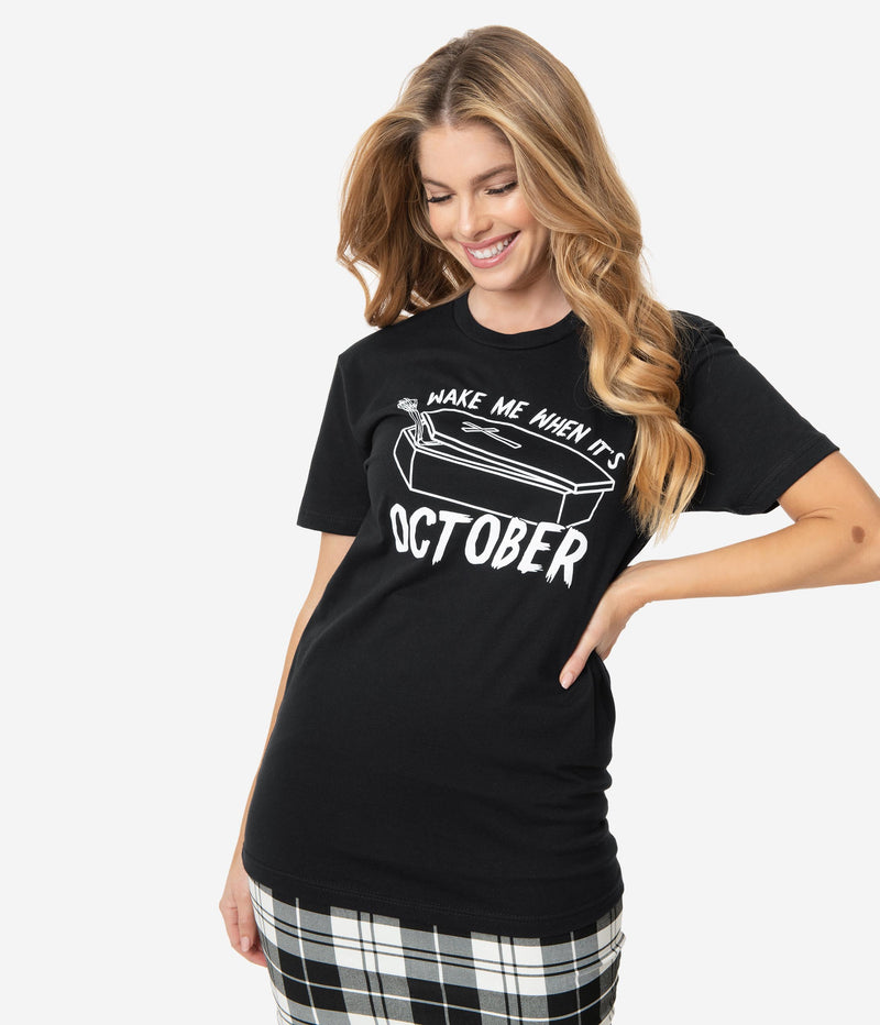 This is a Unique Vintage wake me when it's October black unisex t-shirt, with white letters and the model has a black and white skirt on, with the shirt untucked.