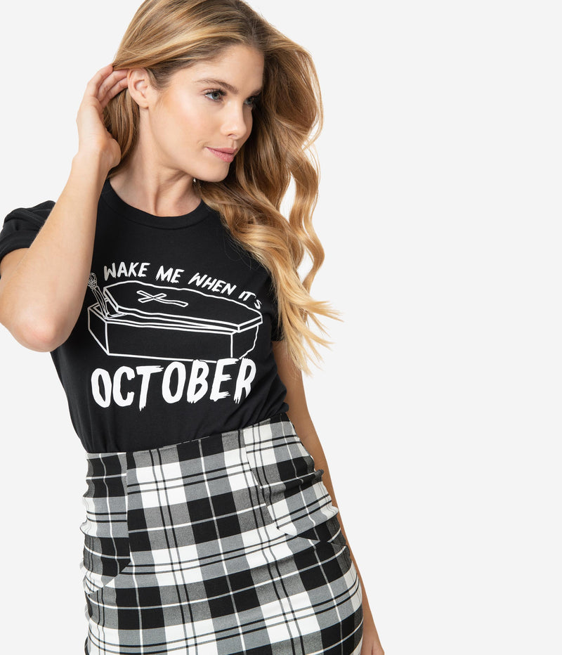 This is a Unique Vintage wake me when it's October black unisex t-shirt, with white letters and the model has a black and white skirt on, with the shirt tucked in.