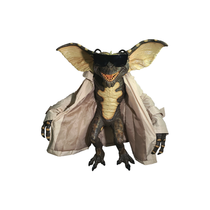 This is a Gremlins Flasher puppet prop and he is green and has big ears and long fingers and is wearing a tan coat and sunglasses.